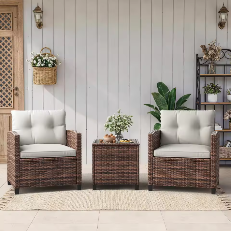 Set kursi rotan outdoor tiga potong, dilengkapi meja kaca dan bantalan duduk, cocok untuk balkon dan teras.